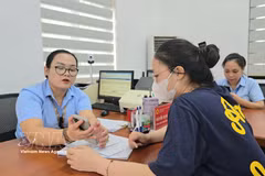 Des fonctionnaires du quartier de Mao Khe guident une citoyenne dans le dépôt en ligne de ses dossiers de certification sur le Portail national de la fonction publique. Photo : TTXVN