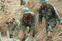 Des soldats s'efforcent de dégager les routes menant aux villages isolés par les inondations. Photo: VNA