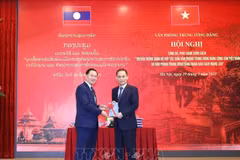 Le Hoai Trung (droite), secrétaire du Comité central du PCV et chef du Bureau du Comité central du PCV, offre un exemplaire du livre à Thongsalith Mangnomek, secrétaire du Comité central du PPRL et chef du Bureau du Comité central du PPRL. Photo : VNA