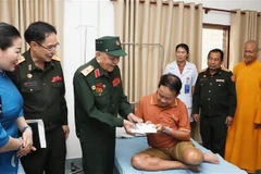 Le général Vo Van Chot, ancien commandant de la 324e division et ancien commandant adjoint de la Région militaire 4, remet le cadeau à un ancien combattant lao. Photo: VNA