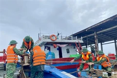 Des gardes-frontières aident des pêcheurs à consolider et à amarrer leurs bateaux. Photo : VNA