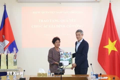 L'ambassadeur Nguyen Minh Vu remet des cadeaux du Têt à Ha Thi E, qui a contribué à la résistance contre l'armée américaine et a reçu un certificat de mérite du Premier ministre vietnamien en 2009. Photo : VNA