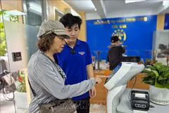 Des habitants effectuent des opérations sur un robot d’IA assistant les démarches administratives au quartier de Cua Nam. Photo d’illustration : VNA