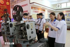 Des jeunes Vietnamiens d’outre-mer découvrent une boussole spécialisée utilisée dans les années 1980, à l’Académie navale. Photo : VNA