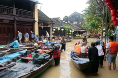 Des touristes prennent des petits barques pour visiter la vieille ville de Hôi An encore inondées. Photo : VNA
