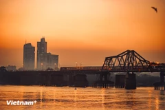 On peut se tenir au loin et contempler le pont Long Bien, où le soleil couchant teinte l'eau de rouge, en observant silencieusement le train entrer lentement dans la ville. Photo: VNA