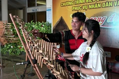 Une jeune vietnamienne d'outre-mer s'essaie le t’rung (xylophone en bambou, très populaire auprès des minorités ethniques des Hauts Plateaux du Centre). Photo: VNA
