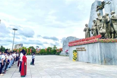 La délégation de jeunes Vietnamiens d’outre-mer devant le monument dédié au Président Hô Chi Minh et aux populations de Quang Binh. Photo: VNA