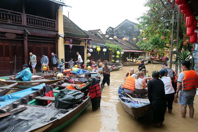 Des touristes prennent des petits barques pour visiter la vieille ville de Hôi An encore inondées. Photo : VNA
