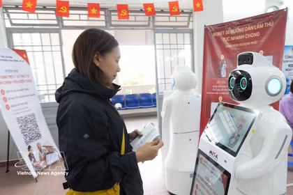 Une citoyenne interagit avec un robot doté d'intelligence artificielle pour obtenir des conseils sur les démarches administratives au centre de services administratifs publics du quartier de Xuan Huong à Da Lat (province de Lam Dong). Photo : VNA