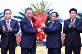 Le Premier ministre Pham Minh Chinh (2e à partir de la droite) offre des fleurs à To Lam (2e à partir de la gauche) après son élection au poste de secrétaire général du Comité central du Parti du 13e mandat. Photo: VNA