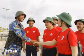 Des représentants du groupe EVN et un soldat sur l'île de Song Tu Tay. Photo : VNA
