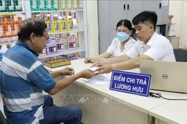 Une personne âgée d'Hô Chi Minh-Ville reçoit une pension dans un bureau de poste. Photo : VNA