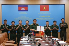 Le général de corps d'armée Huynh Chien Thang, chef adjoint de l'état-major général de l'Armée populaire du Vietnam signe un document sur l'ouverture d'une ligne téléphonique directe entre l'État-major général de l'Armée populaire du Vietnam et le commandement général des forces armées royales du Cambodge. Photo: VNA