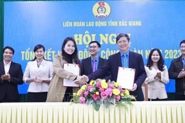 Le dirigeant de la Confédération du travail de la province de Bac Giang signe un accord de coopération sur le programme de bien-être des travailleurs avec la société par actions du commerce international HOGI Group. Photo: VNA