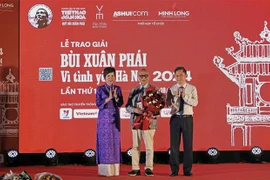 La directrice générale de l’Agence vietnamienne d’information (VNA) Vu Viêt Trang (à gauche) et le vice-président du Comité populaire de Hanoi Hà Minh Hai (à droite) remettent le Grand Prix du Prix «Bui Xuân Phai - Pour l’amour de Hanoi» à l’architecte Hoàng Dao Kinh, à Hanoi, le 8 octobre. Photo : VNA