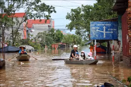 Les habitants de la commune Tri Yen, district de Yên Dung, province de Bac Giang empruntent des barques pour traverser une route inondée, le 13 septembre 2024. Photo : VNA