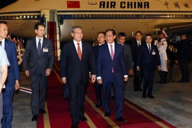 Le Premier ministre chinois Li Qiang (au centre) accueilli à sa descente à l’aéroport international de Nôi Bài, à Hanoi. Photo : VNA