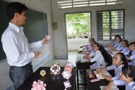 L'enseignant Nguyen Hoang Long fabrique du matériel pédagogique avec des billets de loterie pour mieux enseigner la géométrie à ses élèves. (Source : VNA)