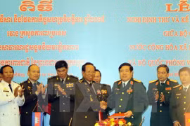 Le ministre vietnamien de la Défense Phung Quang Thanh (droite) et le vice-Premier ministre et ministre de la Défense Tea Banh (gauche) signent un protocole et un plan de coopération entre les deux ministères pour 2015. Photo: VNA