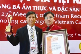 Le médecin Phùng Tuân Giang (droite) reçoit le certificat de «Médecin qui a soigné beaucoup de malades de divers pays par la médecine traditionnelle du Vietnam».