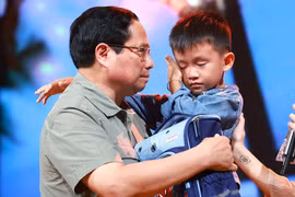 Le Premier ministre Pham Minh Chinh encourage un garçon nommé Nguyen Quoc Bao, dont le père et la sœur aînée ont été emportés par une inondation alors qu'ils traversaient tous les trois un pont dans le hameau de Cau Treo de la commune de Yen Thuan, district de Ham Yen, province de Tuyen Quang. Photo : VNA 