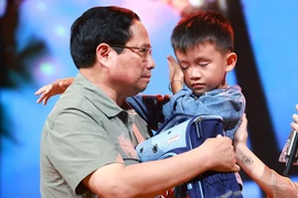 Le Premier ministre Pham Minh Chinh encourage un garçon nommé Nguyen Quoc Bao, dont le père et la sœur aînée ont été emportés par une inondation alors qu'ils traversaient tous les trois un pont dans le hameau de Cau Treo de la commune de Yen Thuan, district de Ham Yen, province de Tuyen Quang. Photo : VNA 