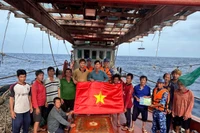 Les forces de l'ordre maritimes de Hô Chi Minh-Ville offrent un drapeau national et diffusent des informations sur la pêche INN aux pêcheurs. Photo: VNA