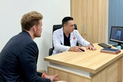 Le docteur Do Lenh Hung (à droite), chef du service de chirurgie reconstructive urétrale de l'hôpital Binh Dan réalise un examen médical auprès du patient, D.F. (47 ans, de nationalité américaine) après une chirurgie reconstructive urétrale. Photo : hôpital Binh Dan