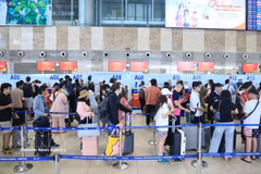 Des passagers effectuent les formalités d'enregistrement au terminal domestique T1 de l'aéroport international de Noi Bai. Photo: VNA