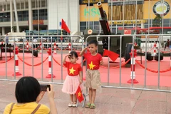 Des enfants, drapeaux nationaux en main, posent devant la batterie de canons. Photo : VNA
