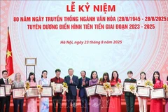 Le secrétaire général Tô Lâm et le ministre de la Culture, des Sports et du Tourisme Nguyên Van Hùng remettent des certificats de mérite et des fleurs pour féliciter les figures exemplaires du secteur culturel. Photo : VNA