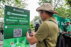 Les gens scannent directement le code QR de la plateforme de commerce électronique VinachemMart dans la rue piétonne du lac Hoàn Kiêm. Photo: VNA