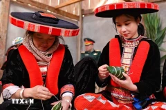 Une touriste de Hanoï (droite) en costume traditionnel de l’ethnie Dao Rouge du district de Nguyen Binh emballe avec empressement des banh chung gù, une sorte de pain riz gluant de forme cylindrique. (Photo : Thanh Tung/VNA)