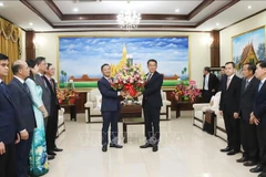 L'ambassadeur Nguyen Minh Tam remet des fleurs de félicitations du secrétaire général To Lam à la partie lao. Photo : VNA 