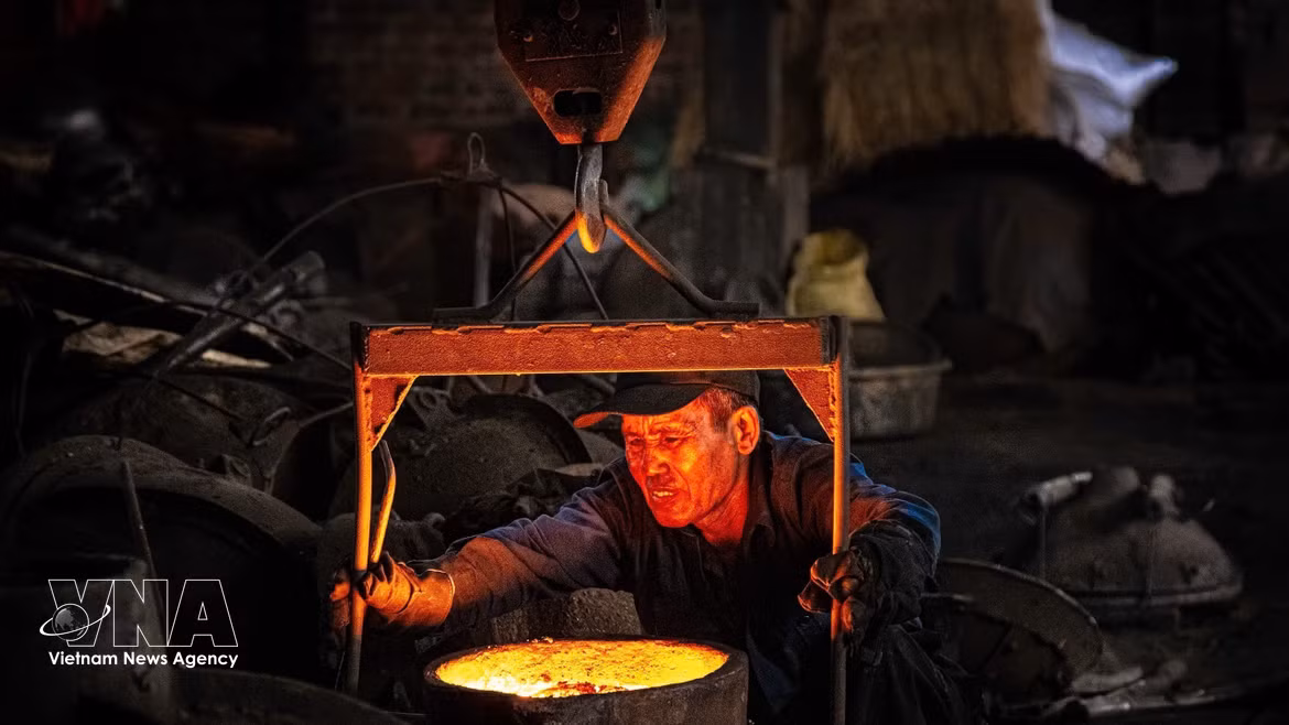 Après avoir versé le fonte en fusion, l'ouvrier retire le moule pour récupérer le produit fini. Photo: VNA