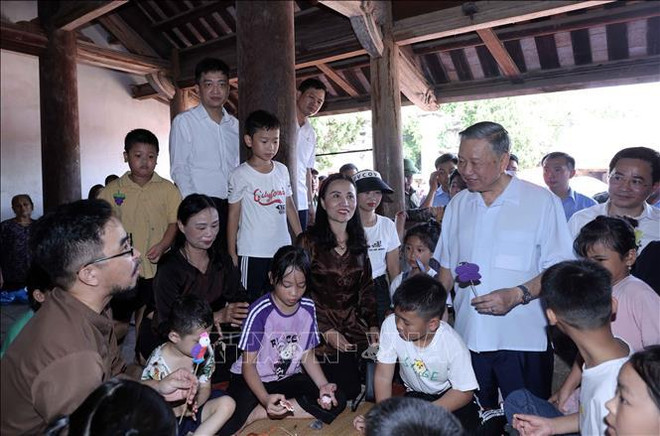 Le président To Lam et des enfants font des figurines en pâte de riz gluant dans la maison communale de Mong Phu, de l'ancien village de Duong Lam. Photo: VNA Lam 2.jpg