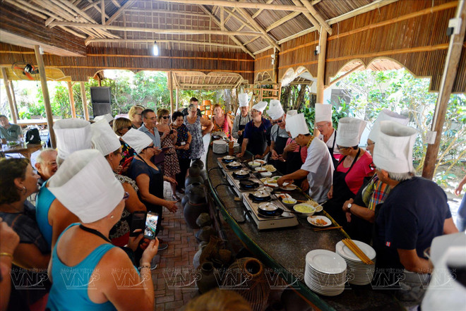 Des étrangers participent à un atelier culinaire au sein d'un restaurant du village de Tra Que. Photo : VI 7.jpg