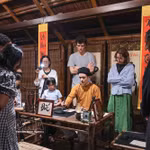 Des touristes assistent à une démonstration de calligraphie lors d'une visite nocturne du Temple de la Littérature à Hanoï. Photo : VNA