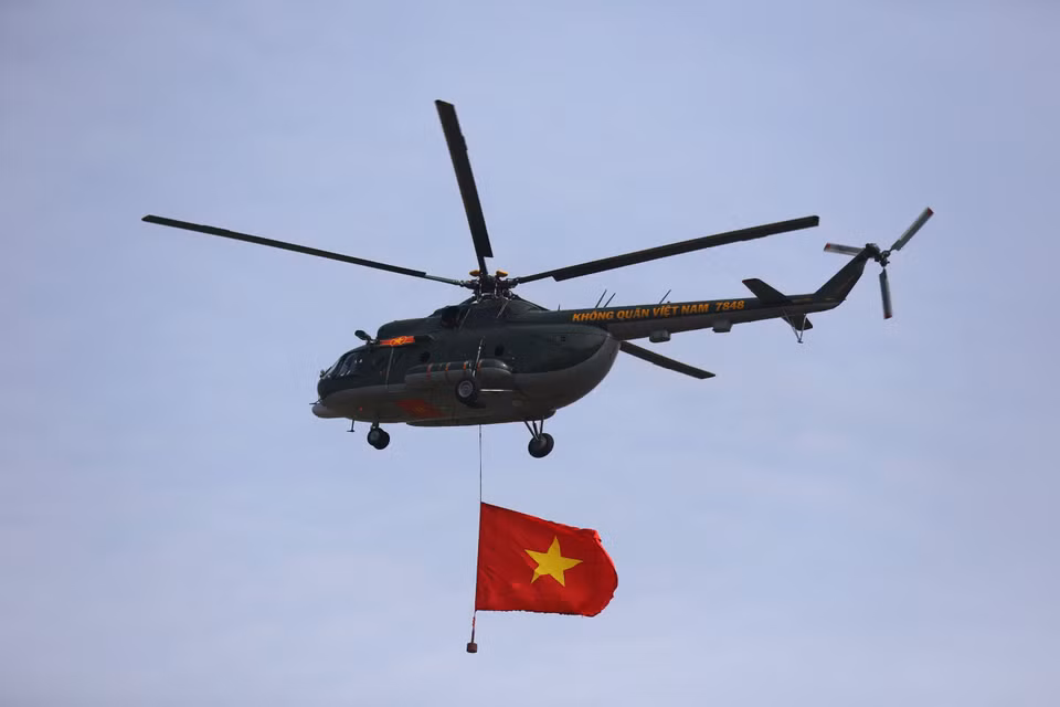 Dans le vaste ciel bleu, un hélicoptère de l'armée de l'air vietnamienne déploie fièrement les couleurs du drapeau national, symbole de la nation.Photo : VNA