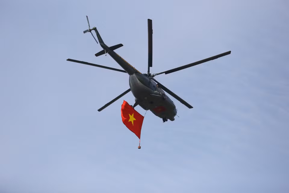 Un hélicoptère de l'armée de l'air vietnamienne arbore le drapeau national dans le ciel. Photo : VNA