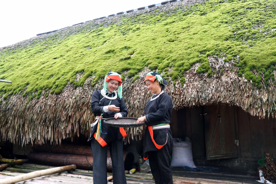 Des femmes Dao à côté d'une maison au toit de mousse dans la commune de Thanh Thuy.