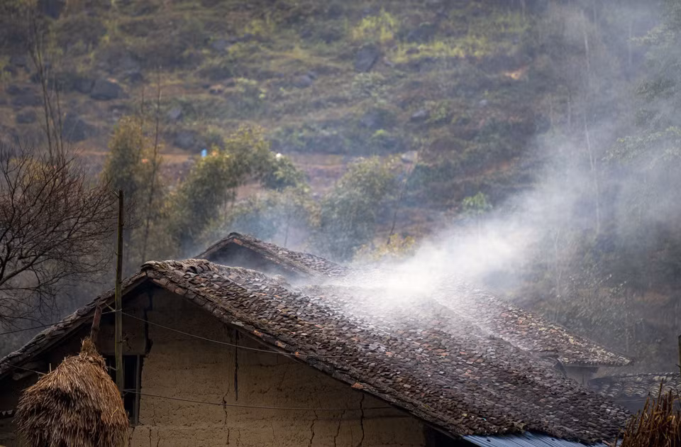 Les fumées s'échappant des cuisines se répandent sur les toits de tuiles des maisons aux murs en torchis.