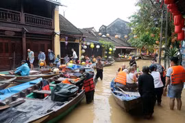Des touristes prennent des petits barques pour visiter la vieille ville de Hôi An encore inondées. Photo : VNA