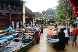 Des touristes prennent des petits barques pour visiter la vieille ville de Hôi An encore inondées. Photo : VNA