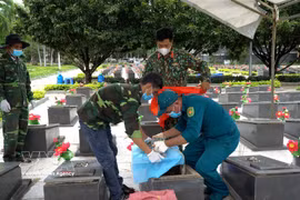 Prélèvement d'échantillons de restes de soldats au cimetière des martyrs de Duc Co. Photo: VNA