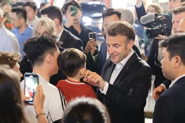 Le président français, Emmanuel Macron, et sa première dame rencontrent des habitants lors d'une promenade dans le Vieux Quartier de Hanoï, le soir du 26 mai. Photo: VNA