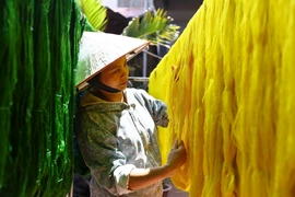 Séchage de la soie après teinture dans l'atelier de tissage de la famille de l'artisan Nguyen Anh Son dans le village de la soie de Van Phuc. Photo : VNA