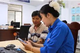 Une membre de l'anntenne de l'Union de la jeunesse communiste Ho Chi Minh à Dak Lak, aide un haibitant local à effectuer une démarche administrative en ligne. Photo: VNA