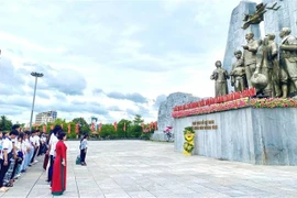 La délégation de jeunes Vietnamiens d’outre-mer devant le monument dédié au Président Hô Chi Minh et aux populations de Quang Binh. Photo: VNA